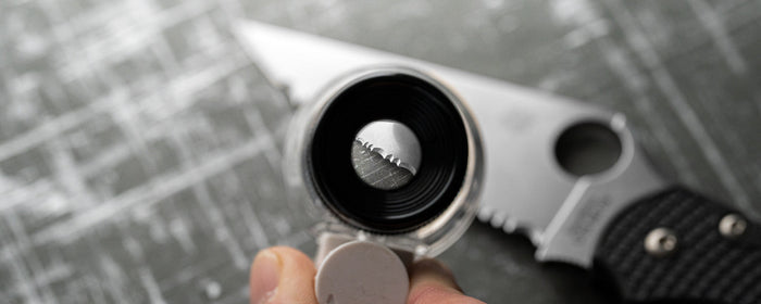 Looking through a loupe at the edge of a serrated blade.