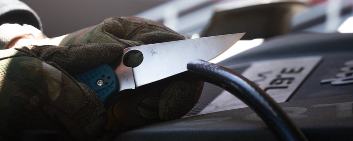 A mechanic using a knife to slice a line.