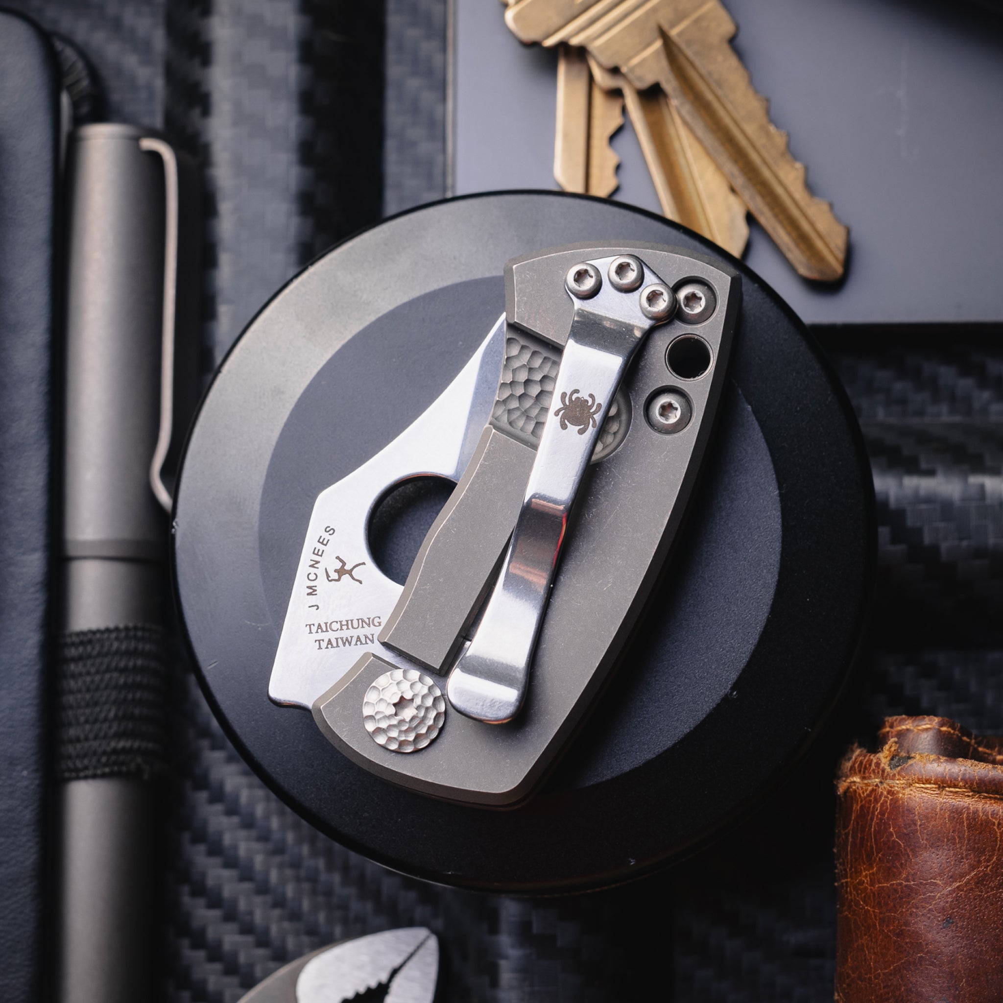 A close up of the McBee pocket knife, pictured with pens, notebooks and keys.