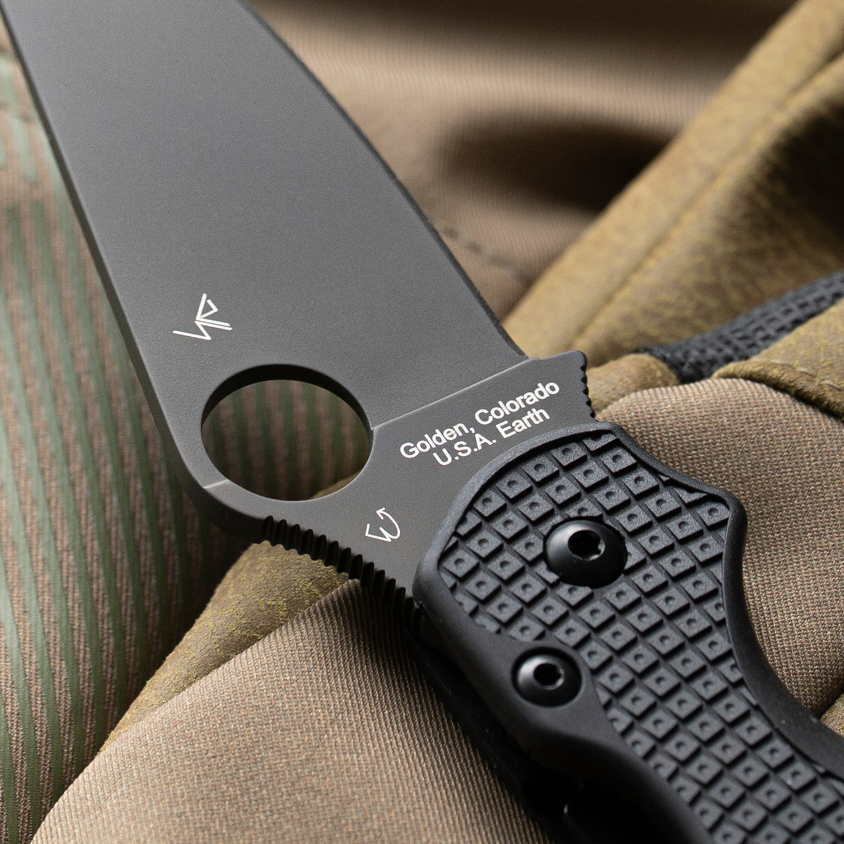 Para Military 2 Lightweight with an all black blade resting on a pair of gloves. Shown is the designer tags of Eric and Sal Glessar with the origins of the knife "Golden, Colorado U.S.A., Earth" on. the base of the blade.